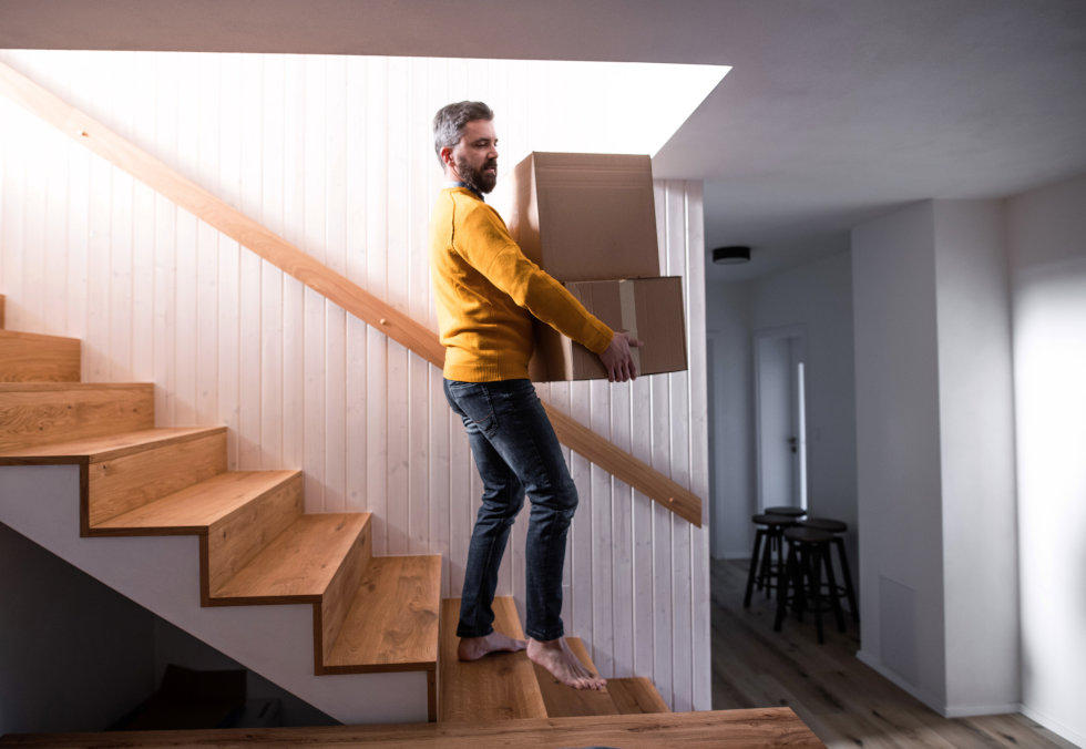 Man walking down the stairs carrying moving boxes